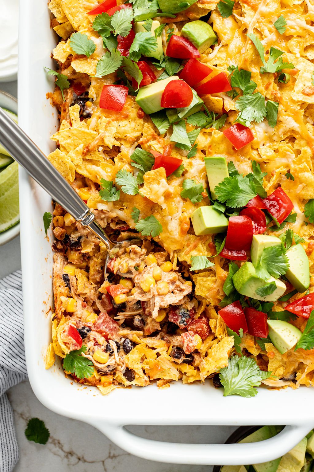 Melty cheese, beans, corn, chicken, and corn chips in a casserole dish.