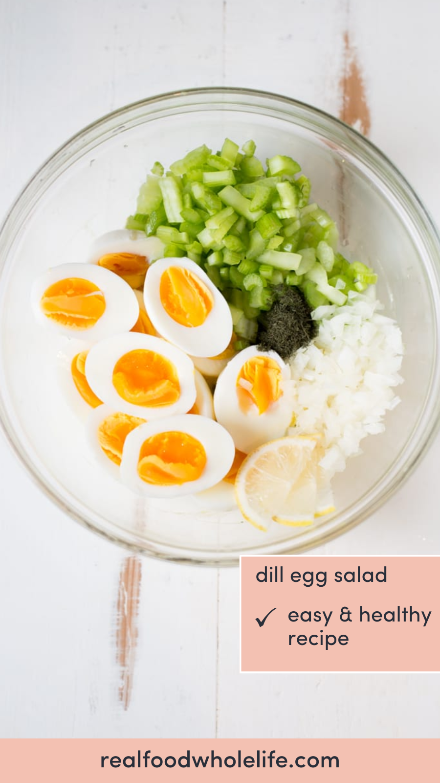 Overhead shot of a glass bowl with the following ingredients placed in sections: boiled eggs, chopped celery, chopped onion, dill, and sliced lemon.
