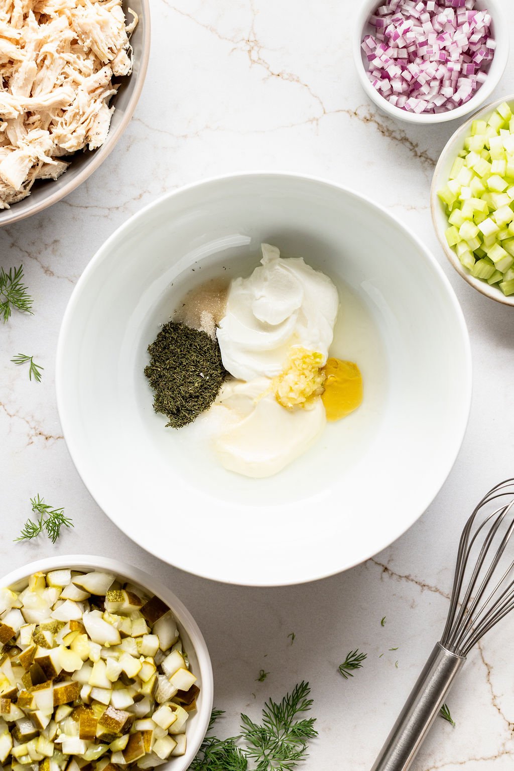 A bowl with mustard, yogurt, mayonnaise, spices, and pickle juice.