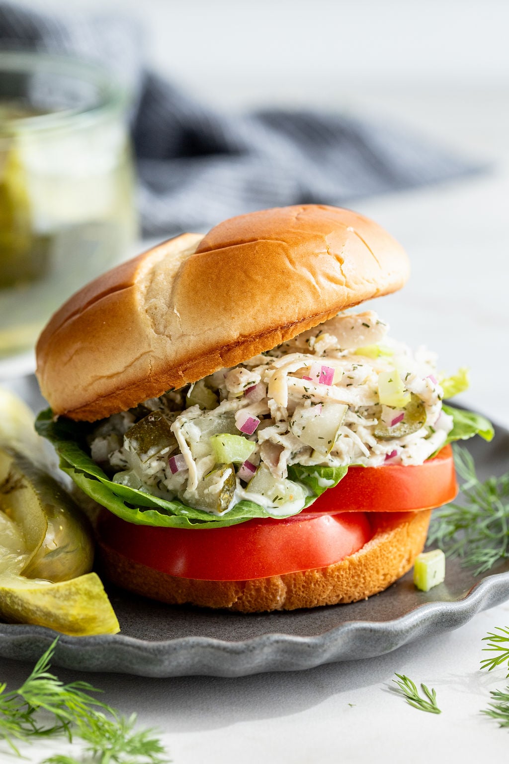 Burger buns filled with lettuce, tomato slices, and creamy dill pickle chicken salad.