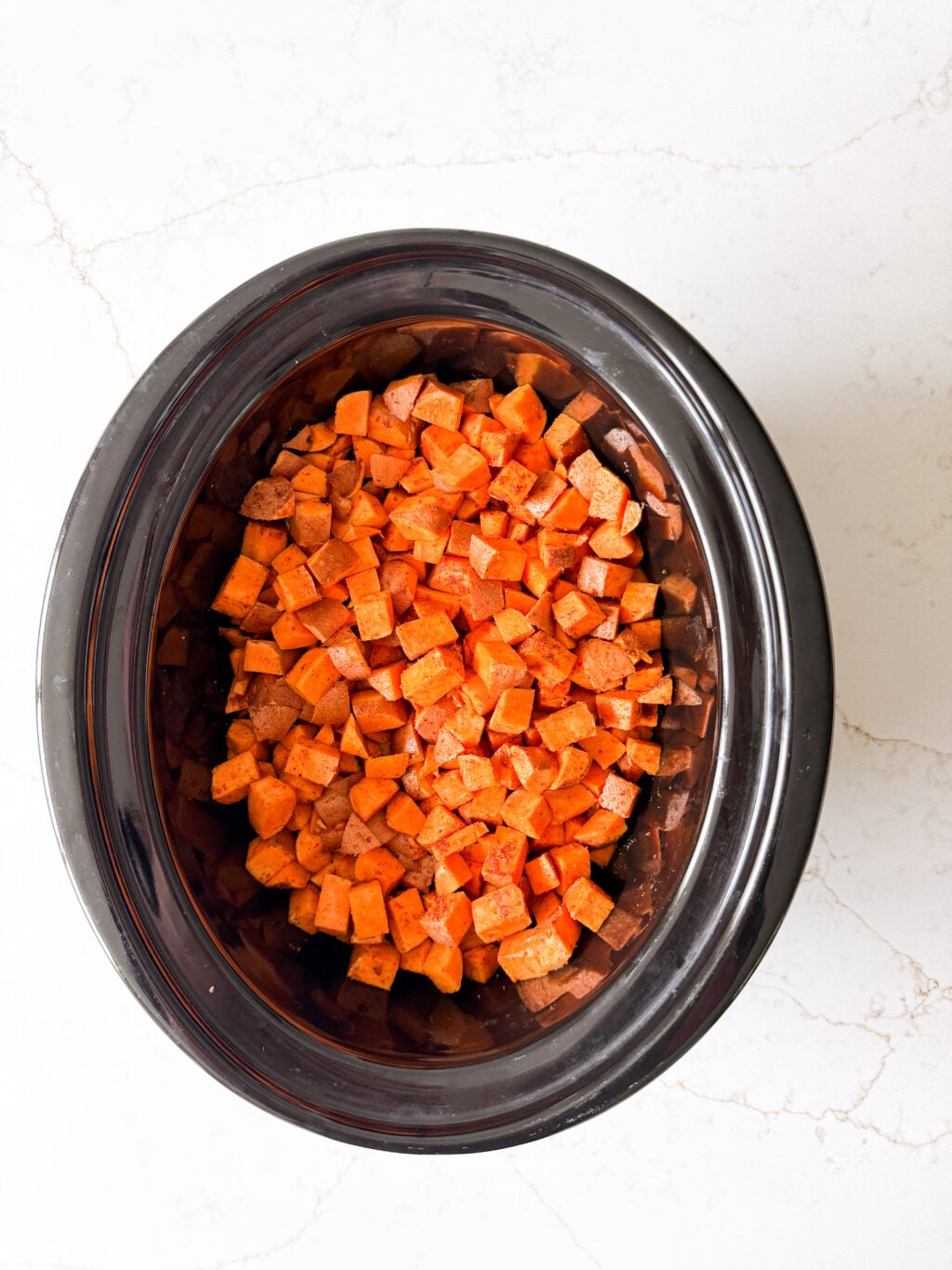 Diced sweet potatoes and ground beef in a slow cooker.