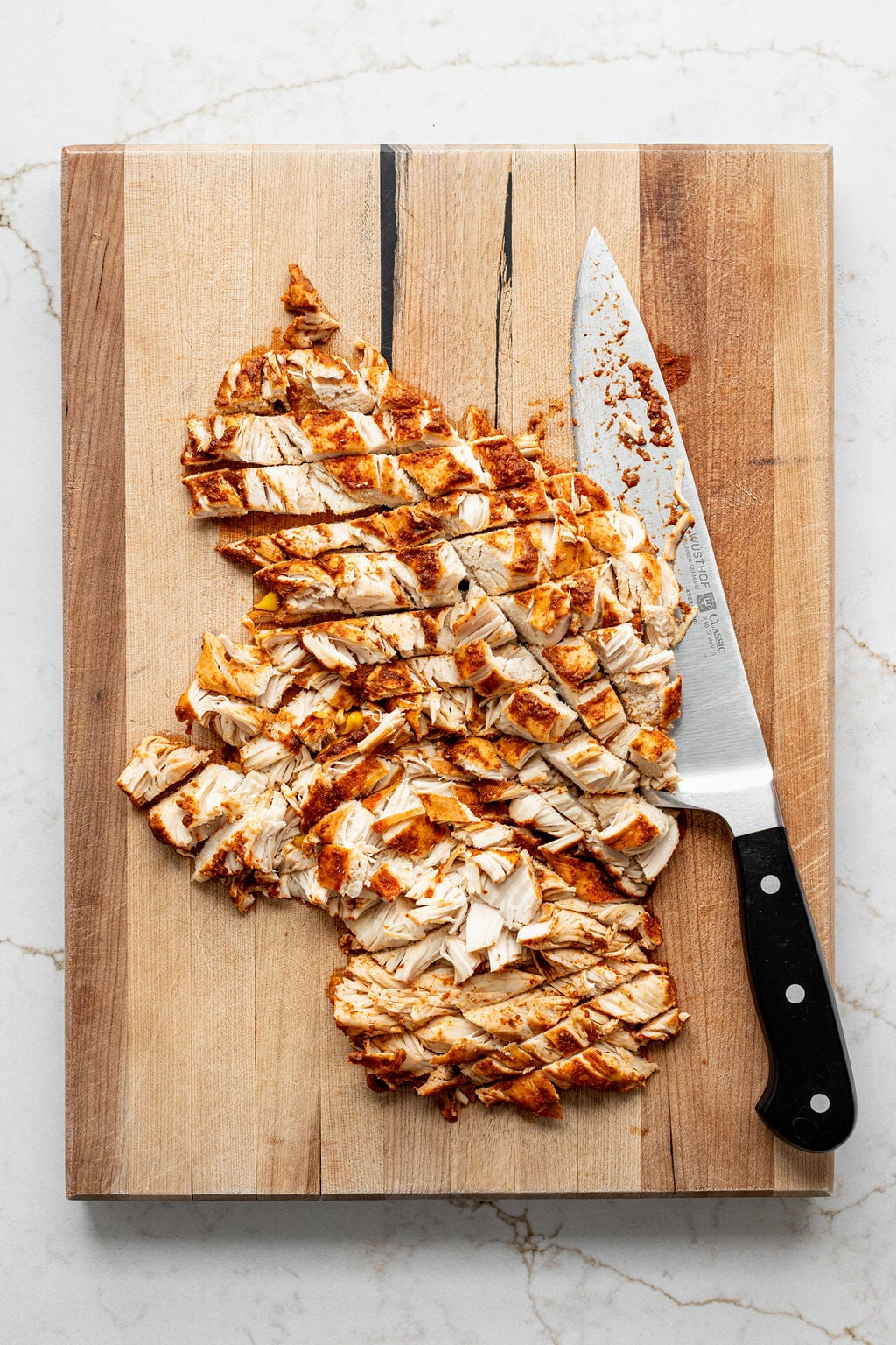 Cooked chicken cut into strips on a cutting board.