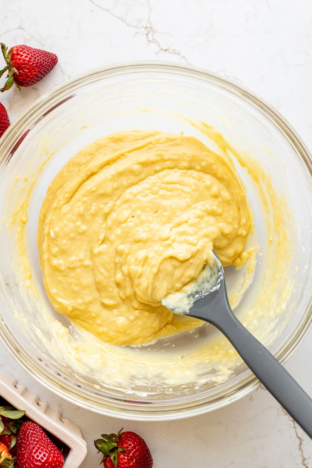 Yellow cake batter in a mixing bowl with a large spoon.