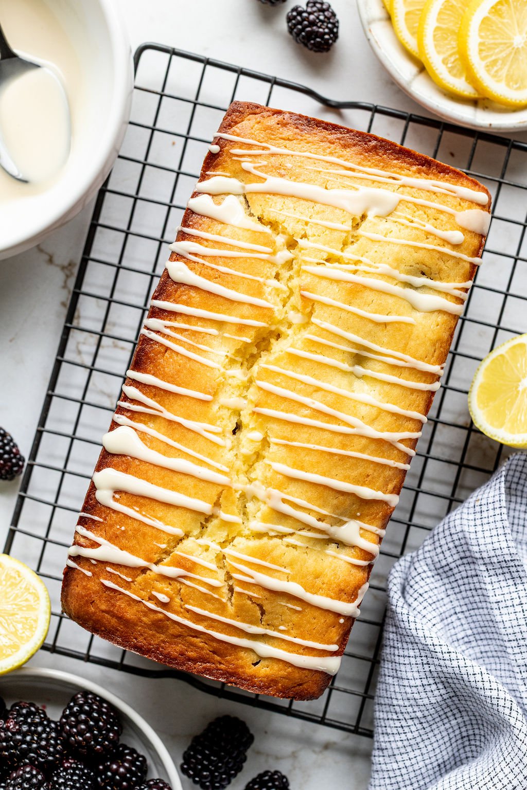 A loaf cake on a cooling rack drizzled with glaze.