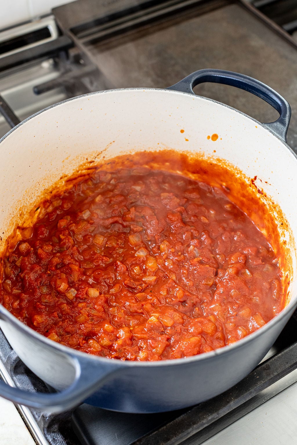 A thick and creamy tomato sauce simmering in a pot on a stove.
