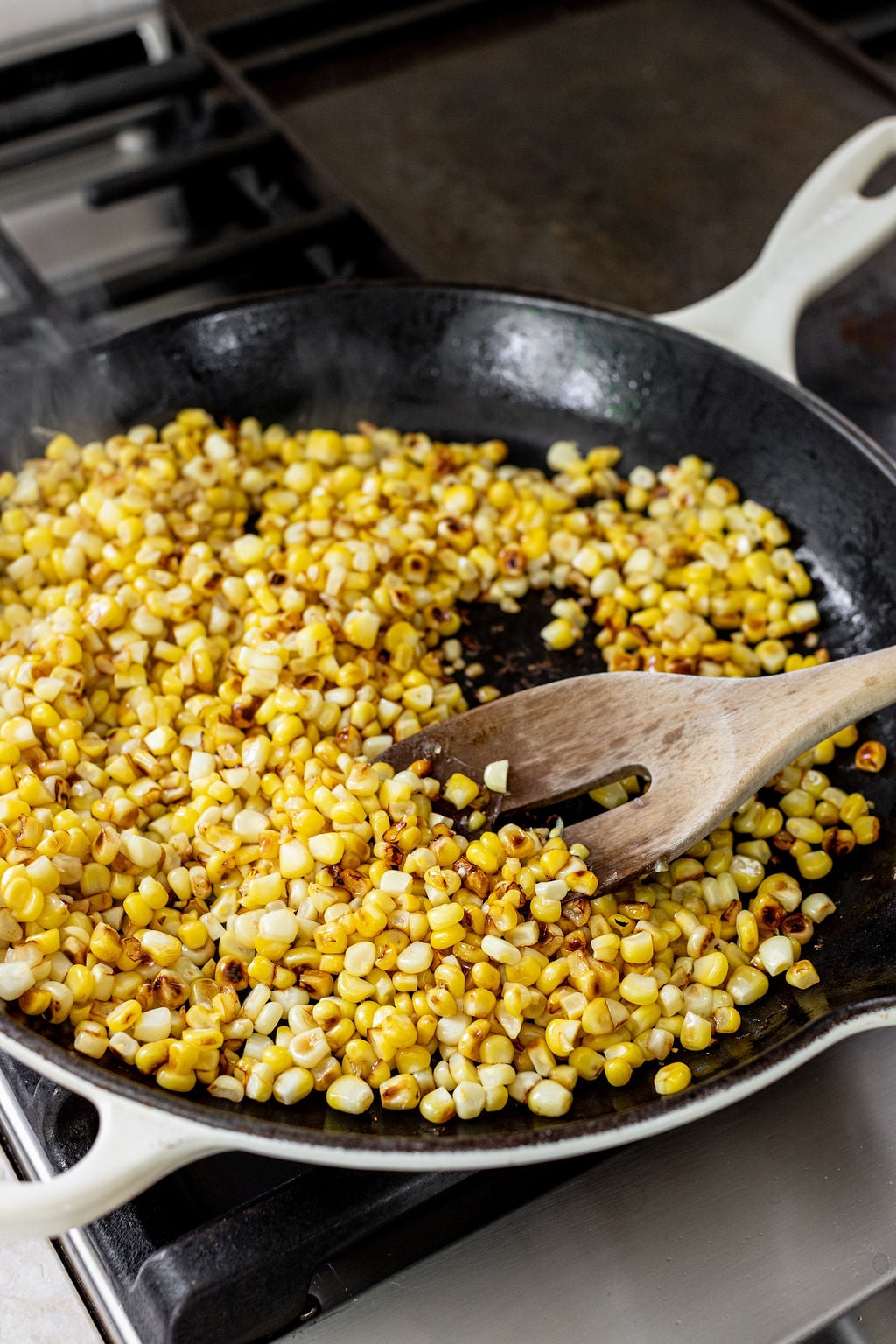 Charred corn kernels in a skillet on the stove.