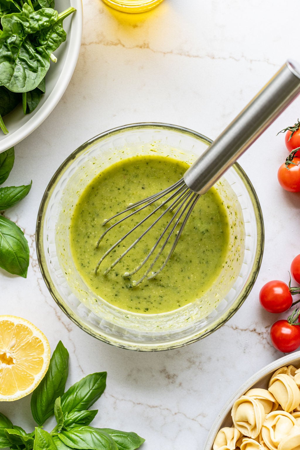 A whisk sitting in a bowl of a creamy vinaigrette.