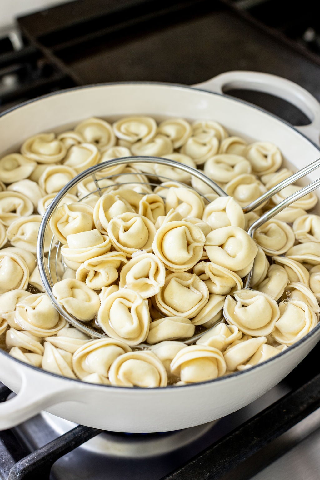 Tortellini boiling in a large pot on a stove.