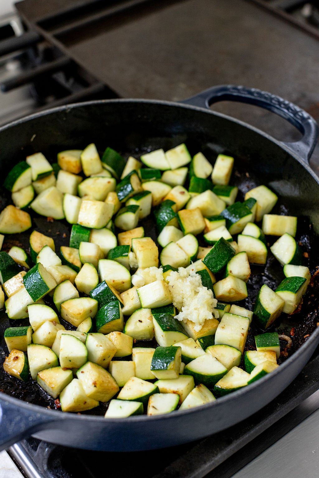 Diced zucchini cooking in a skillet.