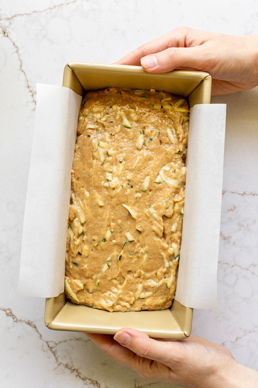 Zucchini bread batter in a metal loaf pan.