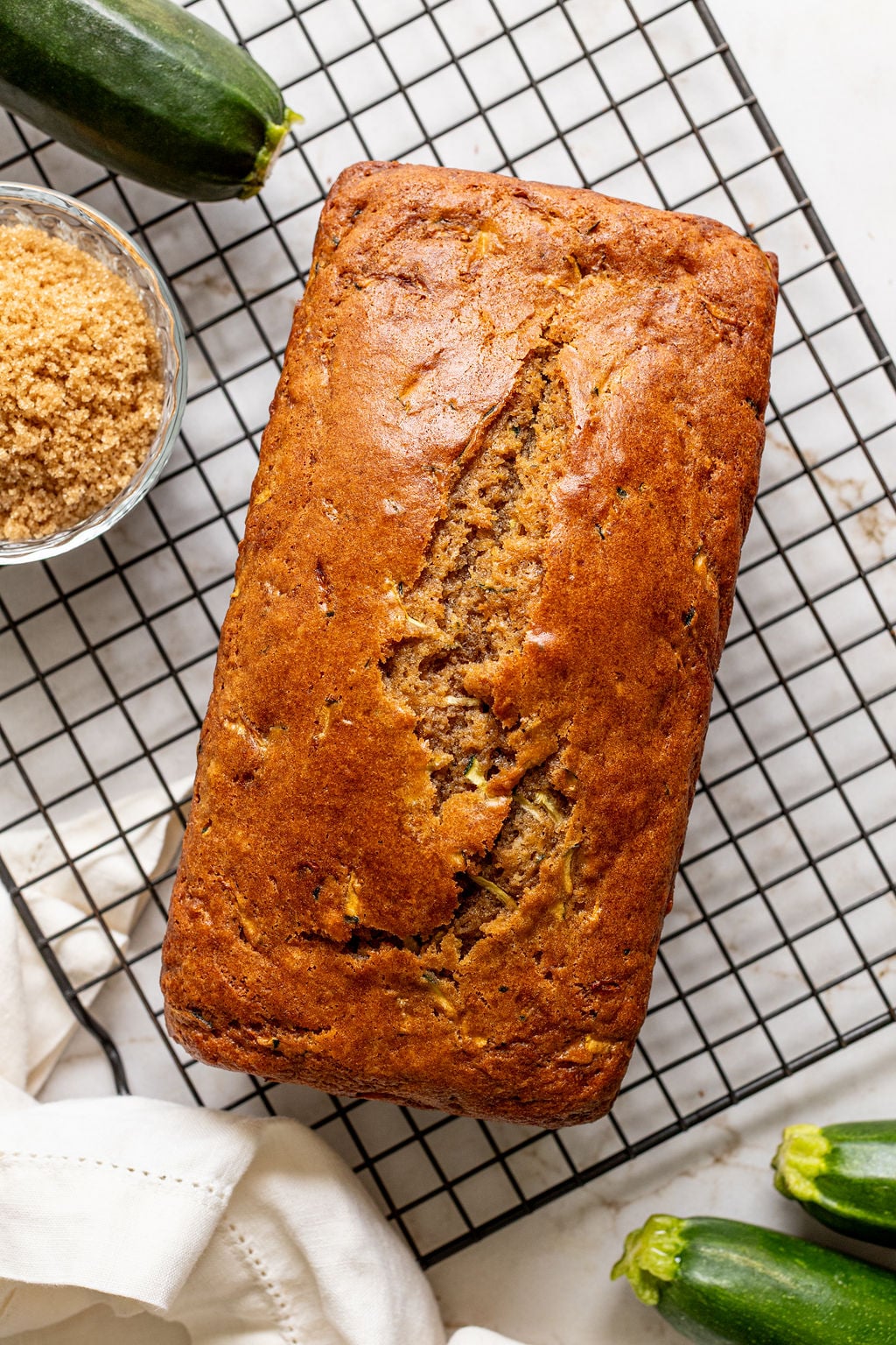 A baked loaf of zucchini bread on a cooling rack.