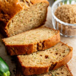 Three slices of zucchini bread next to the rest of the loaf.