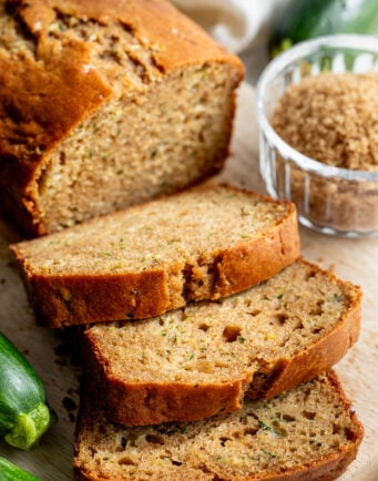Three slices of zucchini bread next to the rest of the loaf.