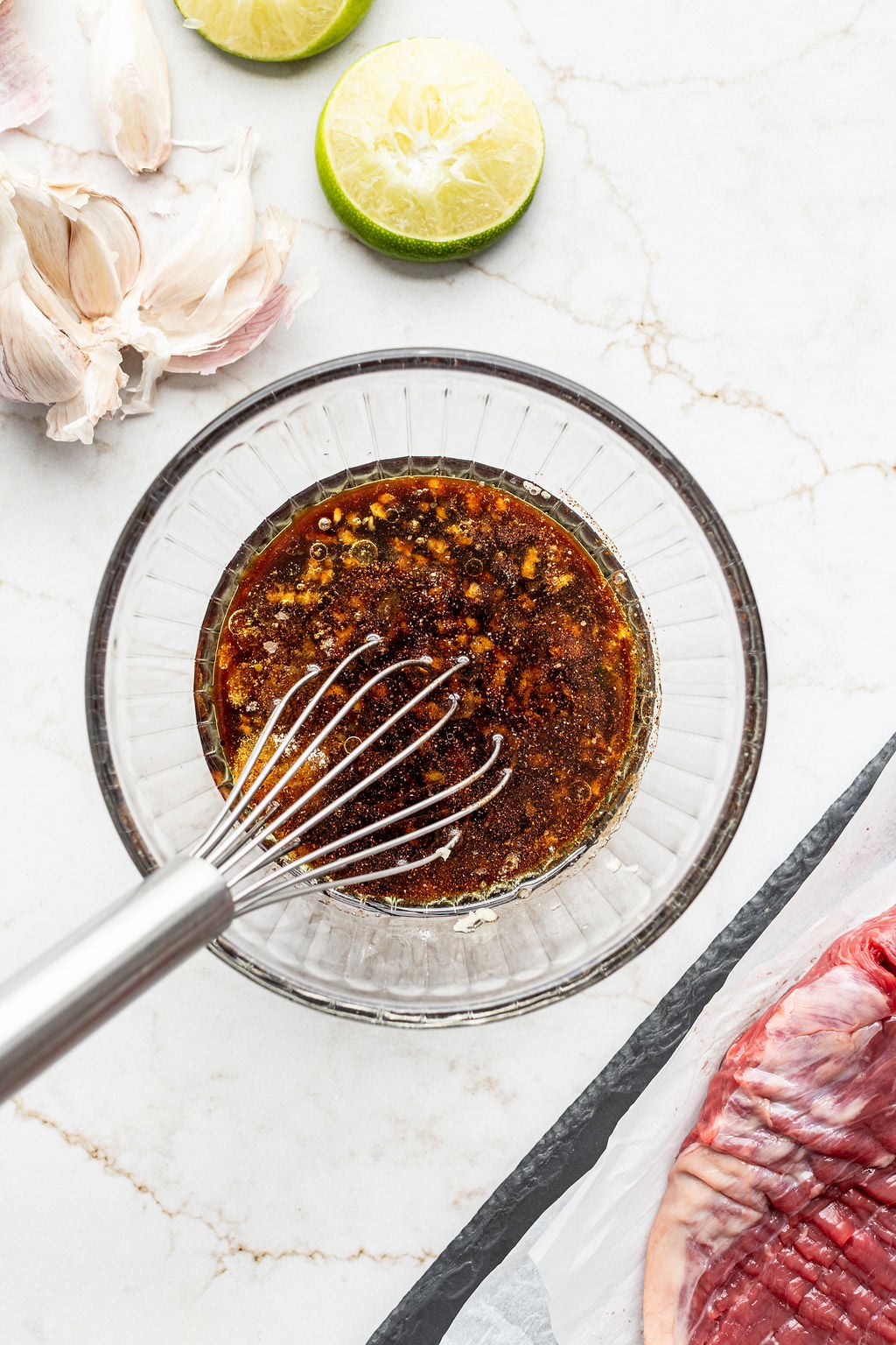 A whisk sitting in a bowl of dark brown sauce.