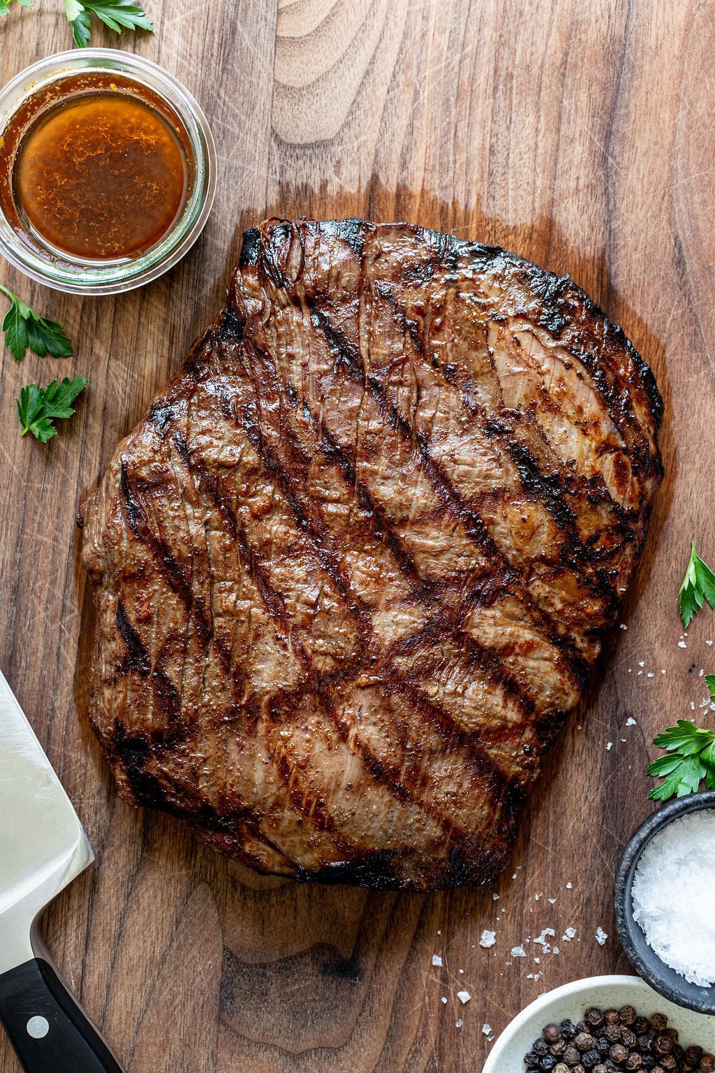 A large cut of grilled flank steak on a cutting board.
