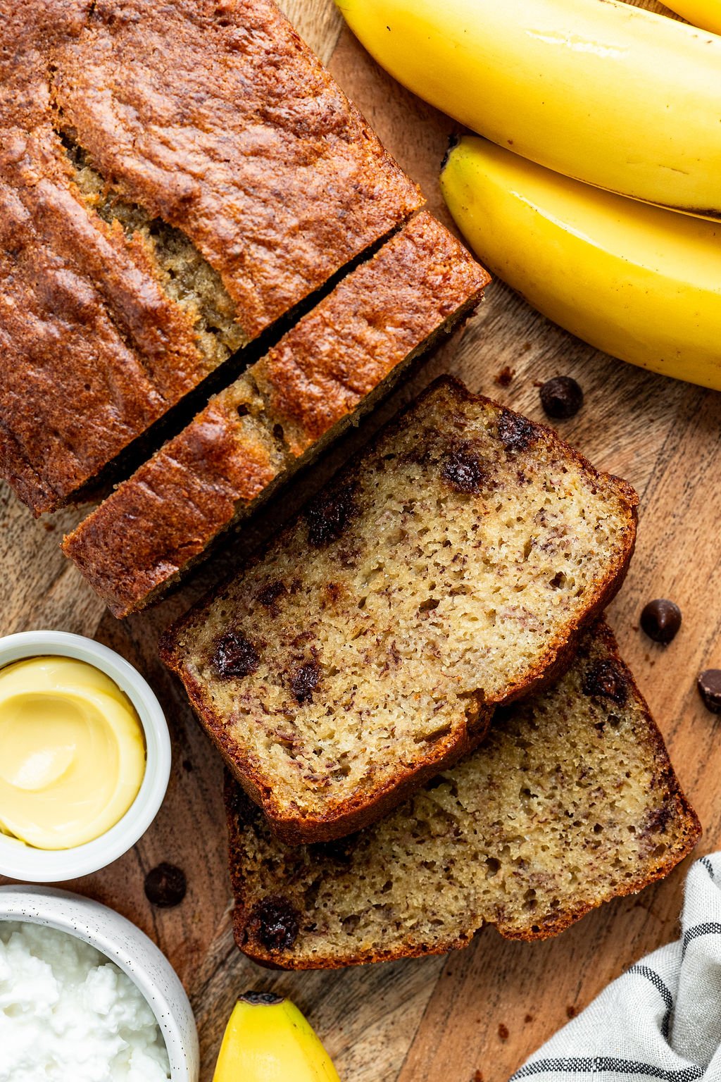 Sliced loaf of banana bread with chocolate chips on a wooden surface.