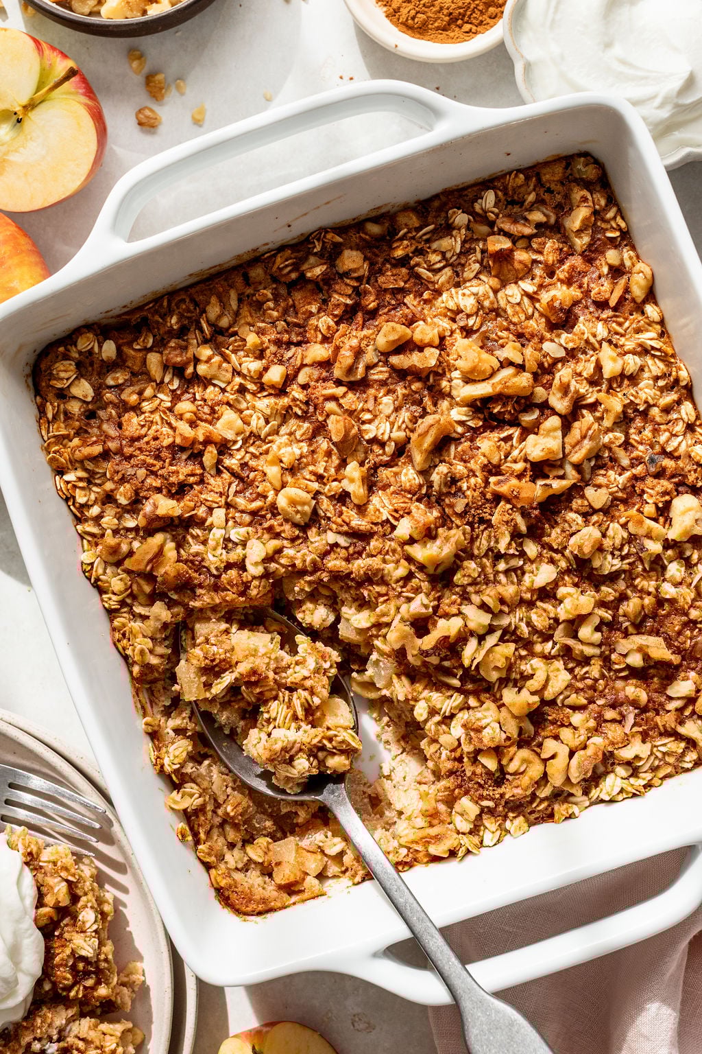 A baked oatmeal dish with a golden, crumbly topping is shown in a white baking pan.