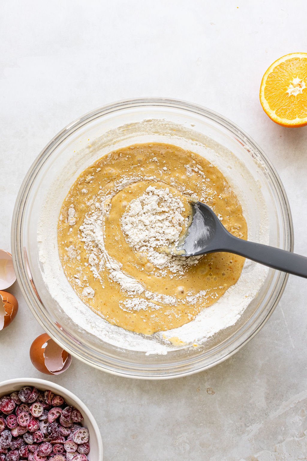 A glass bowl with quick bread batter being mixed with a spatula.