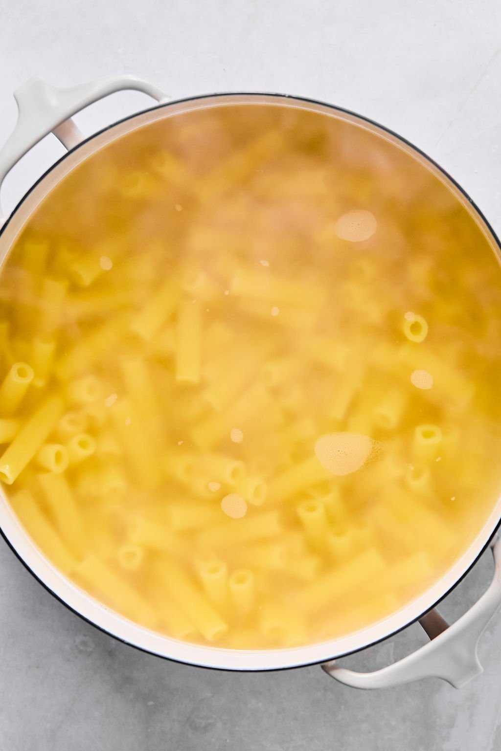 A pot filled with boiling water and pasta cooking inside.