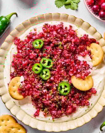 A cream cheese dip topped with finely chopped cranberry salsa and garnished with sliced jalapeños.