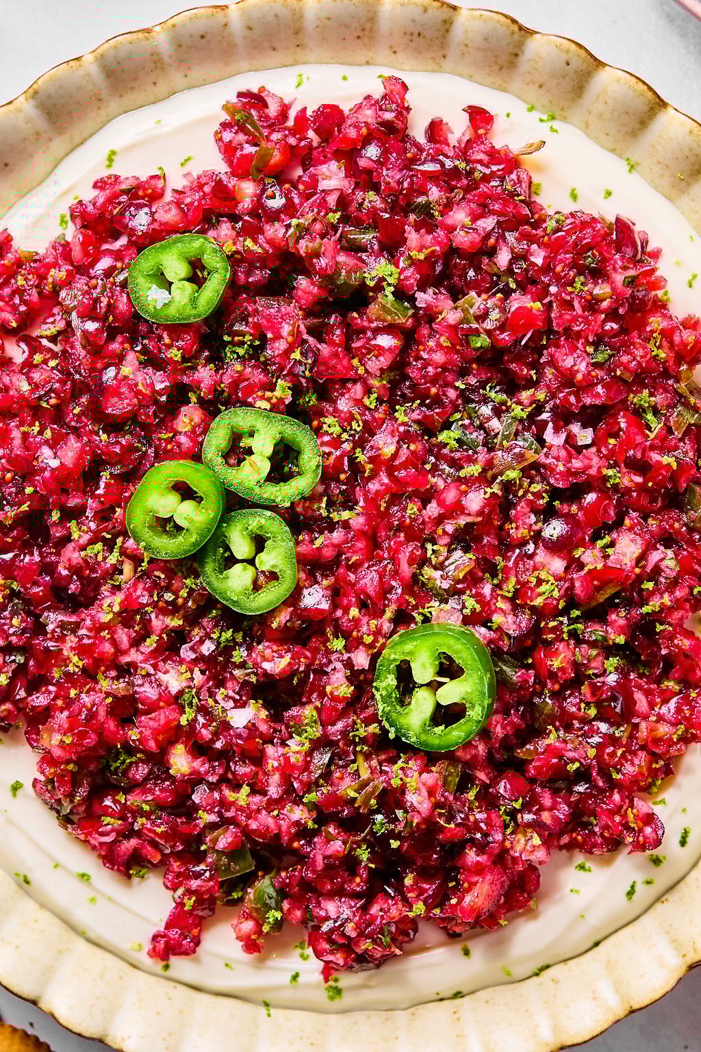 A plate of finely chopped cranberry dip topped with thin slices of fresh green jalapeño.