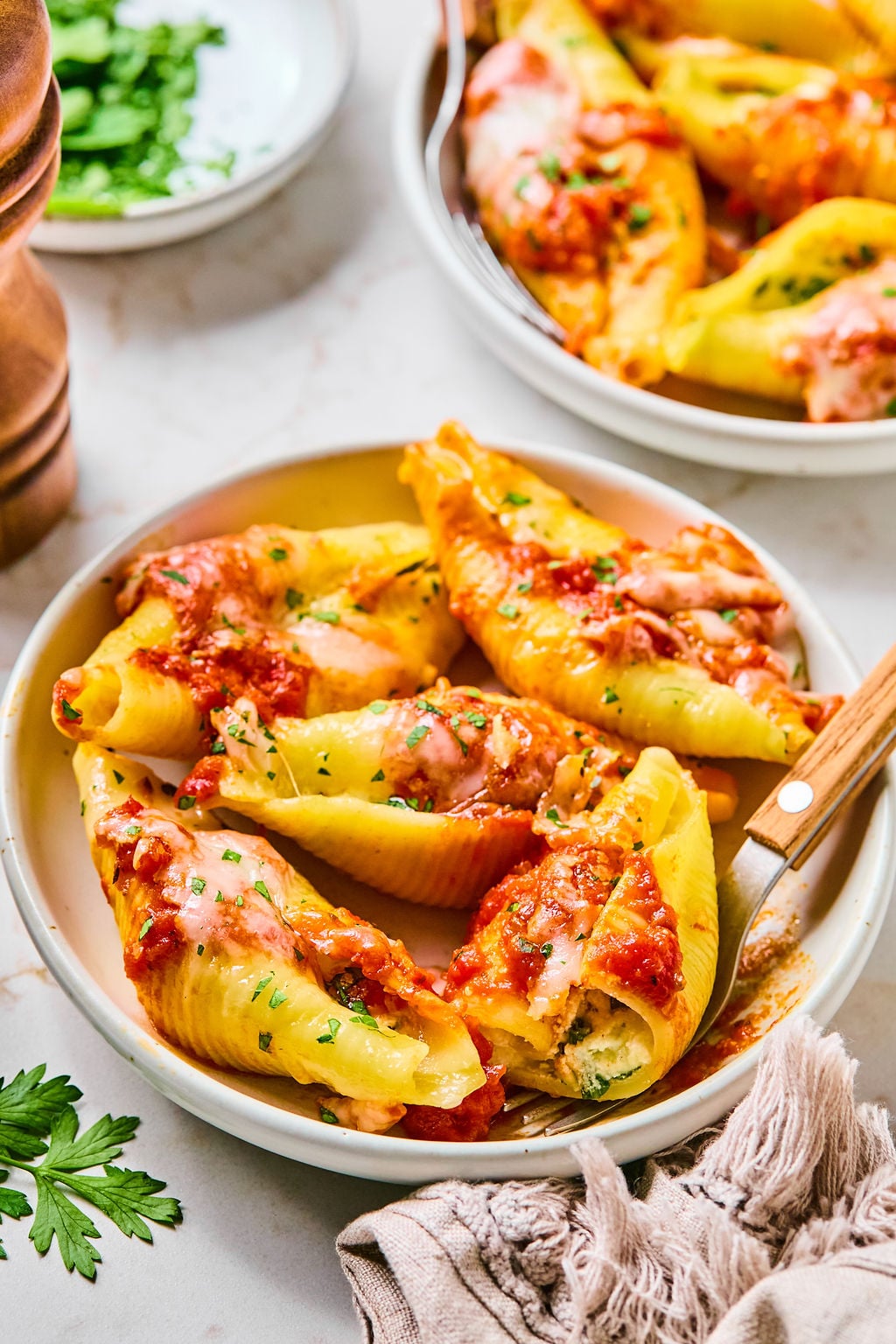 A plate of stuffed pasta shells topped with tomato sauce and melted cheese, garnished with chopped herbs.