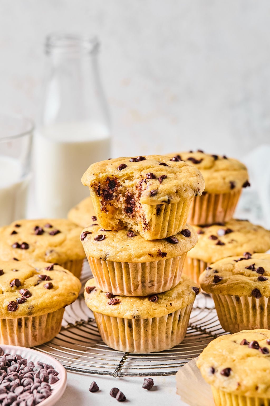 A stack of three chocolate chip muffins with a bite taken out of the top one.