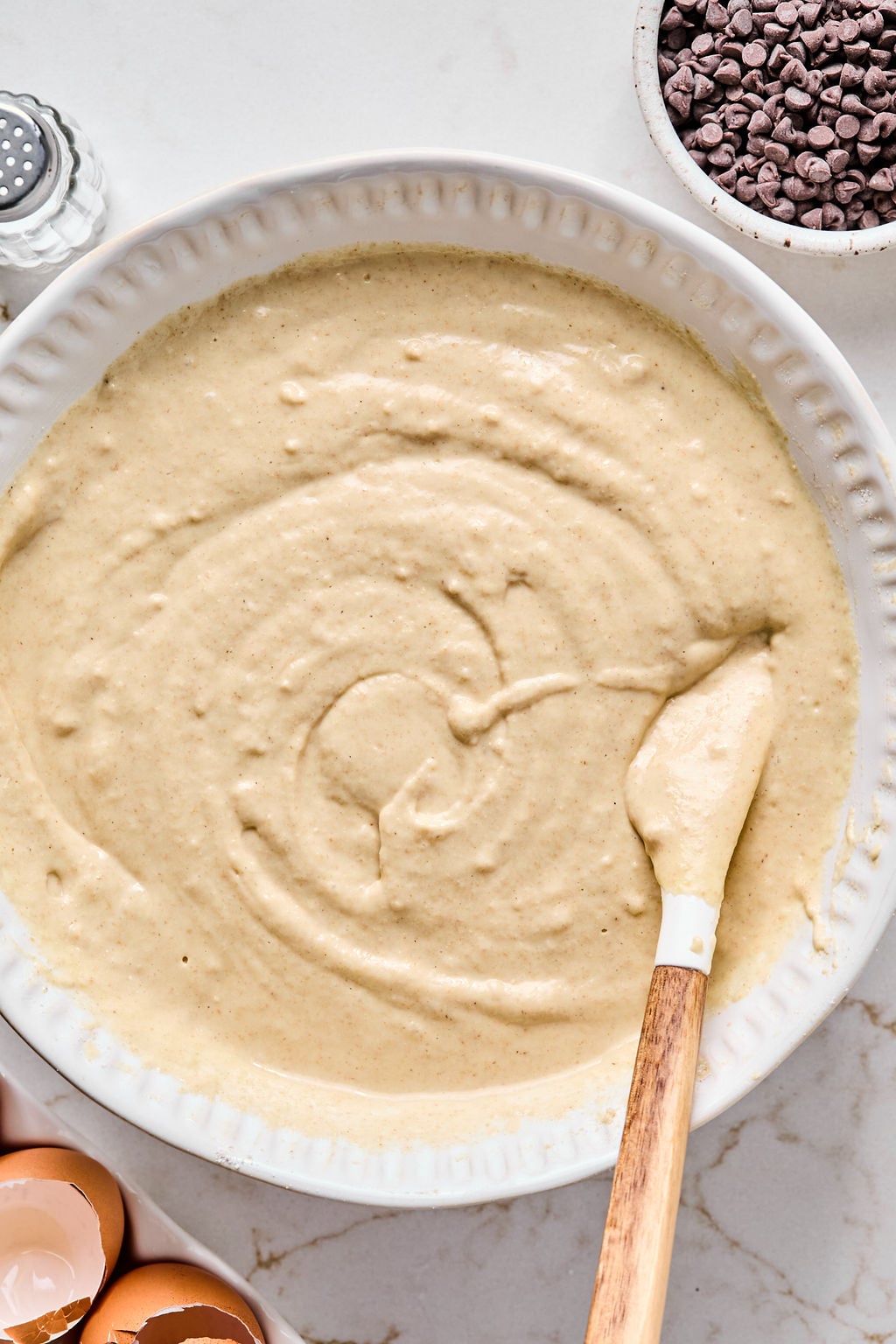 A mixing bowl filled with smooth pancake batter being stirred with a spatula.