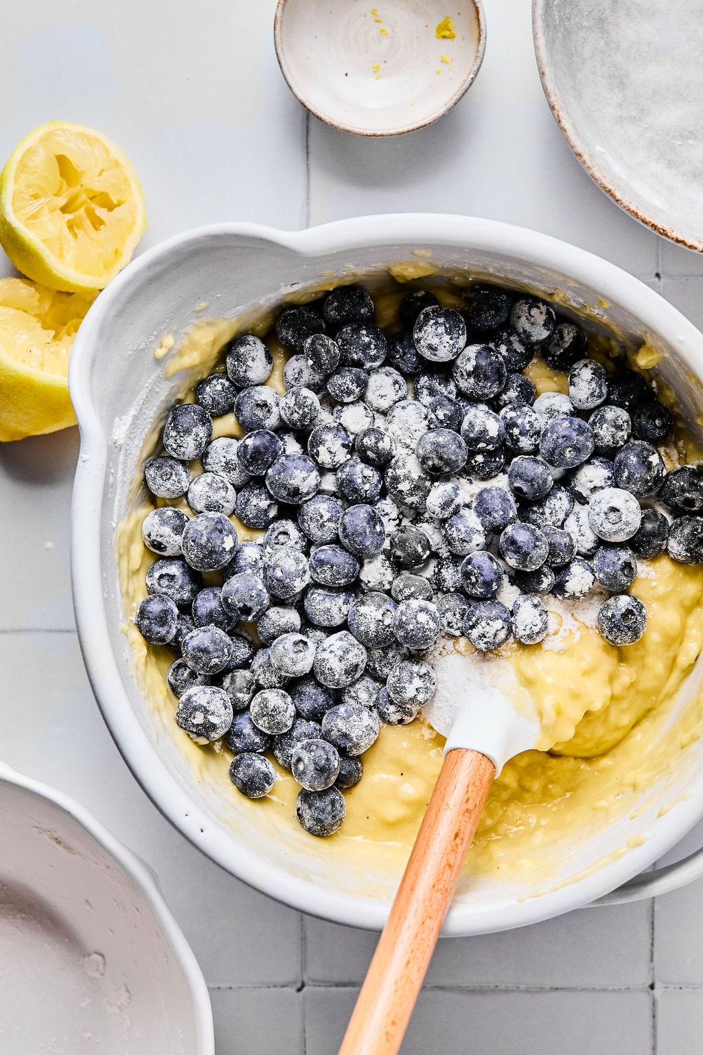 A mixing bowl with batter, fresh blueberries, and a spatula.