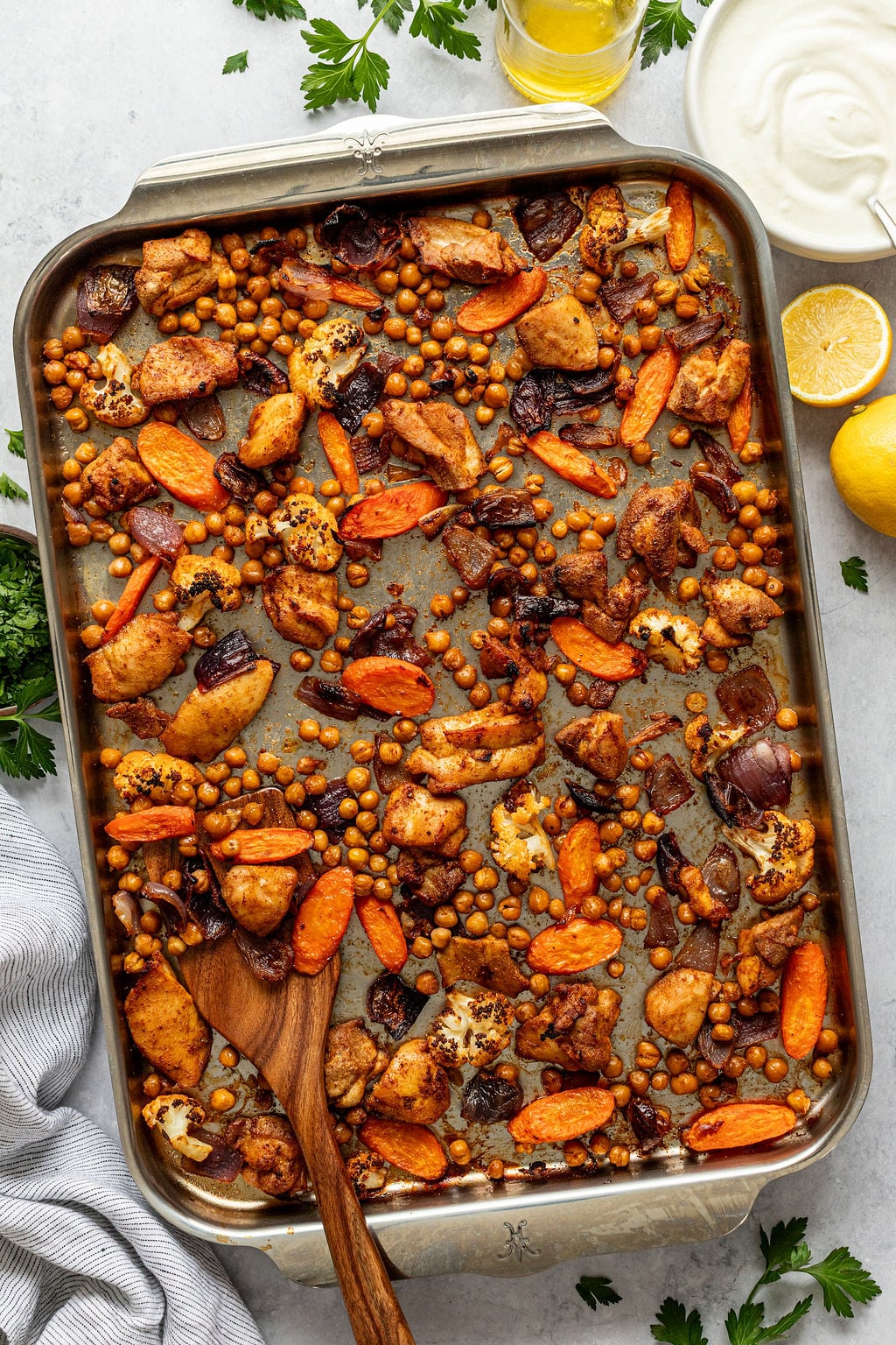 Roasted, cubed chicken and chopped carrots, cauliflower, red onion, and chickpeas on a sheet pan.