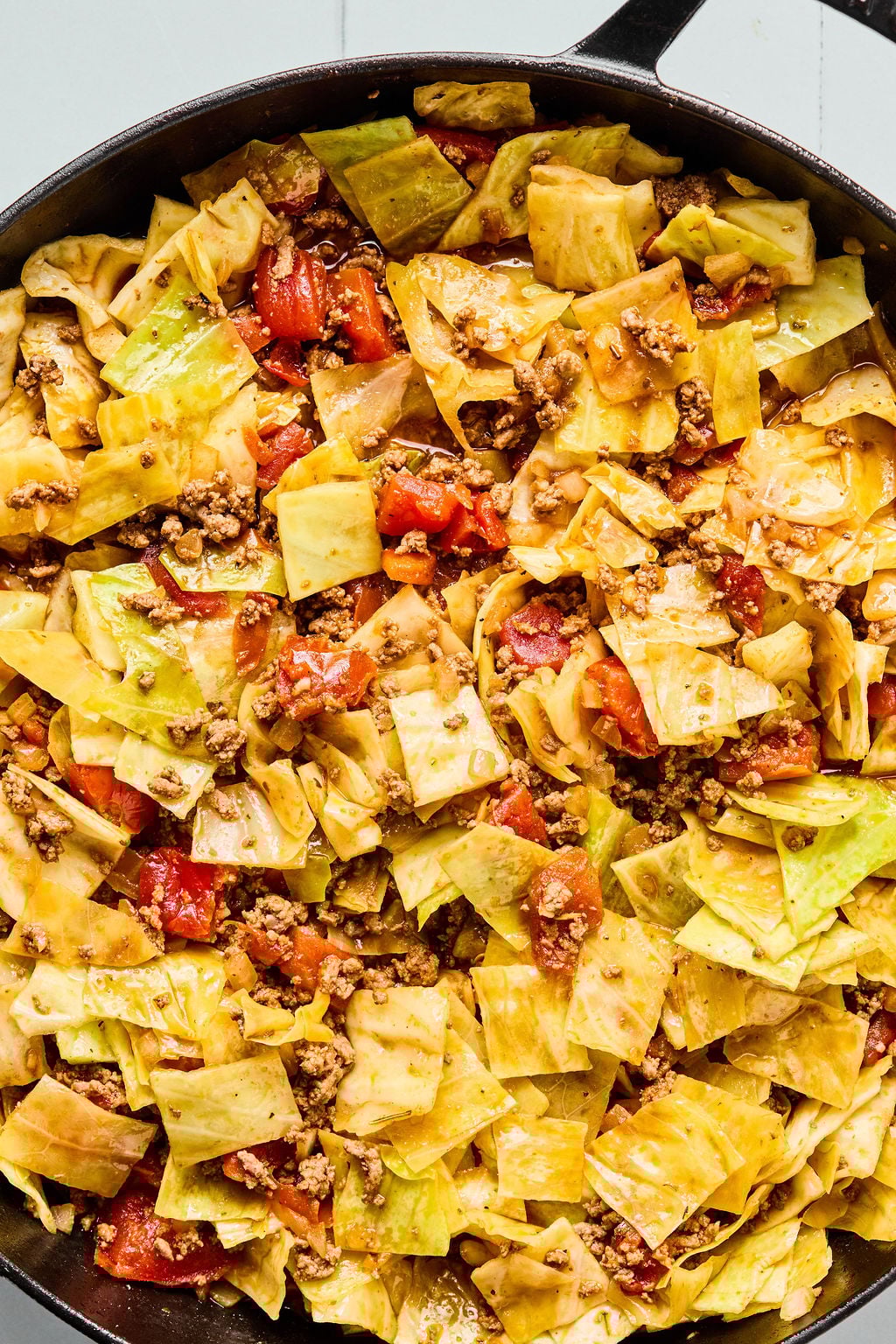 A skillet filled with cooked cabbage, ground beef, diced tomatoes, and seasonings, all mixed together.