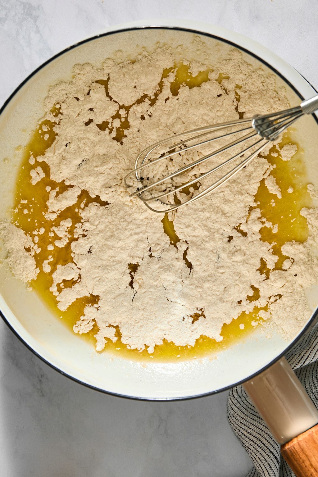 Flour being whisked into melted butter in a skillet.