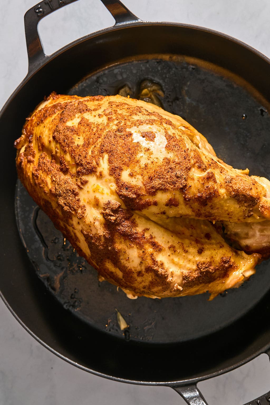 A seasoned, roasted turkey breast in a cast-iron skillet.