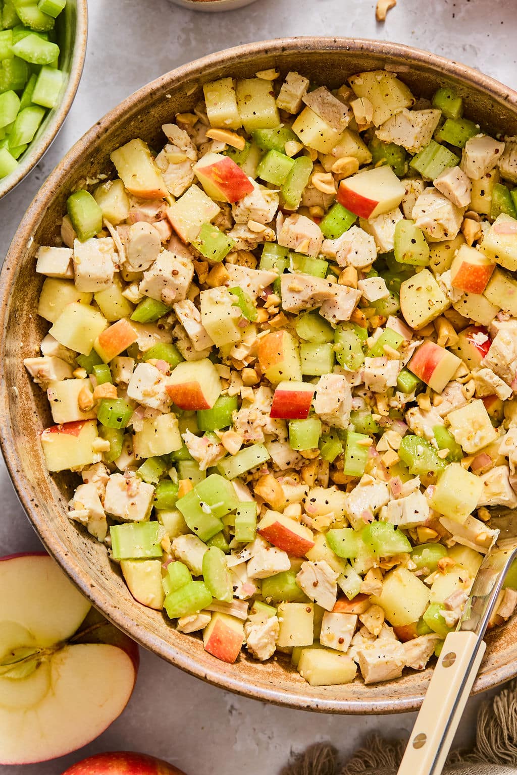 Chicken salad with diced apples, celery, and nuts in a ceramic bowl.